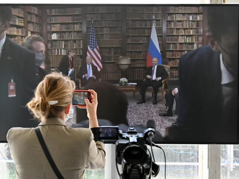 A journalist takes a picture of the screen displayed in the press room showing US President Joe Biden and Russian President Vladimir Putin during the US-Russia summit at the Villa La Grange, in Geneva 