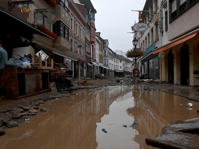 A resident stands next to damaged furnitures in a flooded street in Bad Neuenahr-Ahrweiler, western Germany, on July 15, 2021. German authorities said late July 15, 2021 that at least 58 people had likely died in massive storms and flooding in the country's west, an increase on the earlier toll of 45 dead