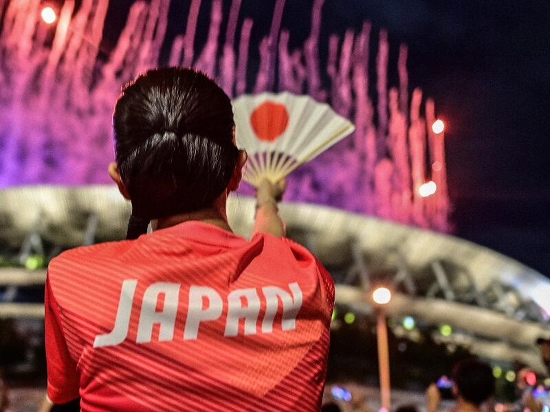 A Japanese supporter looks on as fireworks light up the sky over the Olympic Stadium during the opening ceremony of the Tokyo 2020 Olympic Games,