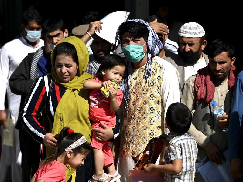 A family stand in a queue to submit their passport applications at an office in Kabul on July 25, 2021. Dozens begin lining up at the passport office in Kabul before dawn most days, and by eight in the morning the queue already stretches for a good hundred metres. 