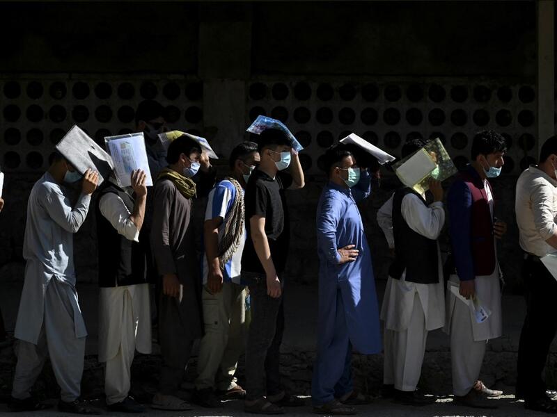 People stand in a queue to submit their passport applications at an office in Kabul on July 25, 2021. Dozens begin lining up at the passport office in Kabul before dawn most days, and by eight in the morning the queue already stretches for a good hundred metres. 