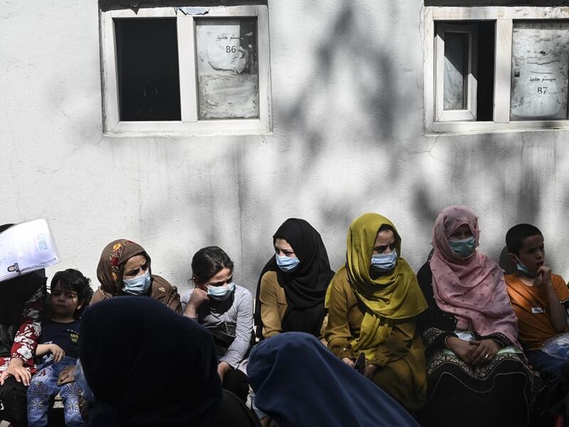 People sit in a queue to submit their passport applications at an office in Kabul on July 25, 2021. Dozens begin lining up at the passport office in Kabul before dawn most days, and by eight in the morning the queue already stretches for a good hundred metres. 