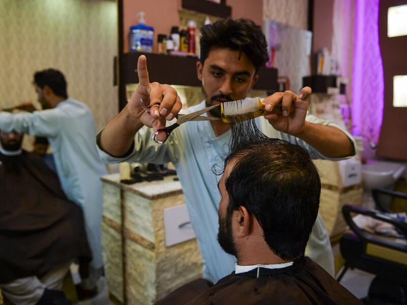 In this picture taken on September 19, 2021, a barber attends a customer at his shop in Herat.