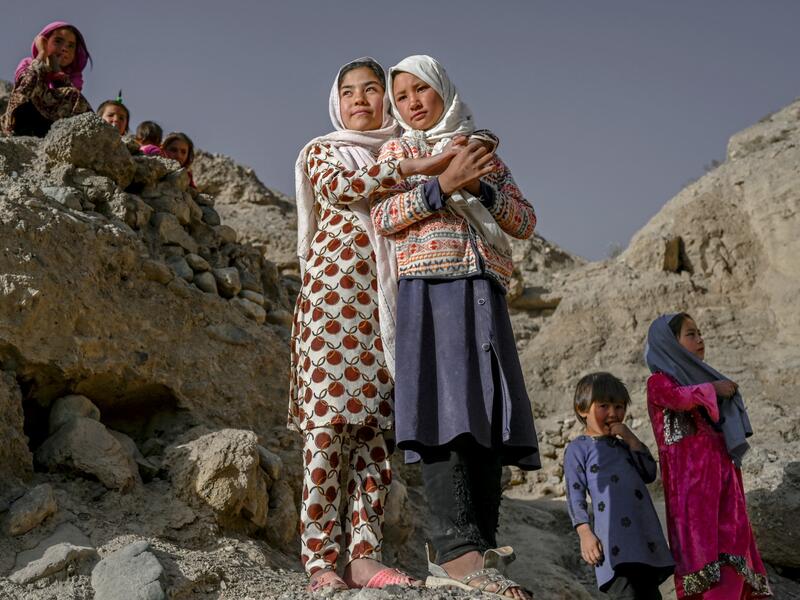 In this picture taken on October 3, 2021, Hazara ethnic people stand on a cliff pockmarked by caves where people still live as they did centuries ago in Bamiyan. 