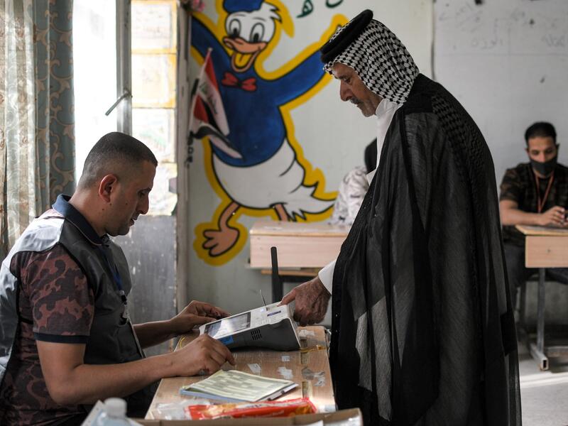 A voter scans his fingerprint a scanner while registering his vote at a polling station in the southern city of Nasiriyah in Iraq's Dhi Qar province, during the early parliamentary elections on October 10, 2021. (Photo by Asaad NIAZI / AFP)