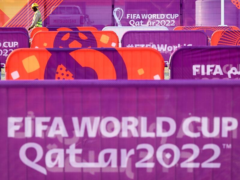 A worker walks past FIFA World Cup banners outside the Khalifa Stadium in Doha on November 6, 2022, ahead of the Qatar 2022 FIFA World Cup football tournament. (Photo by Kirill KUDRYAVTSEV / AFP)