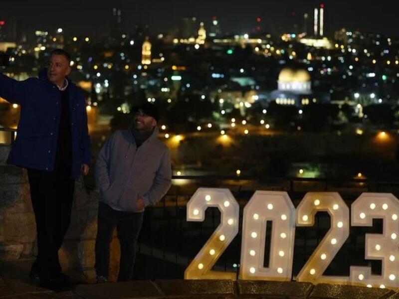 اشخاص يقفون لالتقاط صورة لافتة مضاءة 2023 في جبل الزيتون في القدس ، 31 ديسمبر 2022 (ا ف ب)