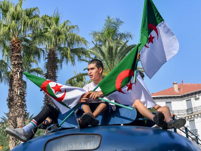 شبان جزائريون يرفعون علم بلادهم (أ ف ب)