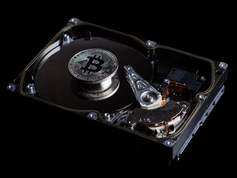 Silver Bitcoin coin on the opened HDD disk