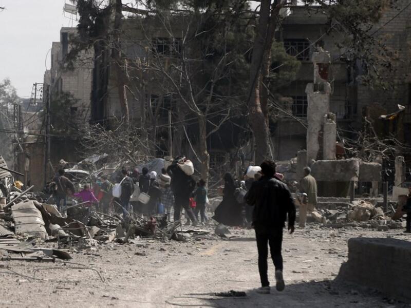 People carry their belongings as they flee their homes in the town of Hamouria in Syria's eastern Ghouta region on Mar. 15, 2018. (ABDULMONAM EASSA / AFP)