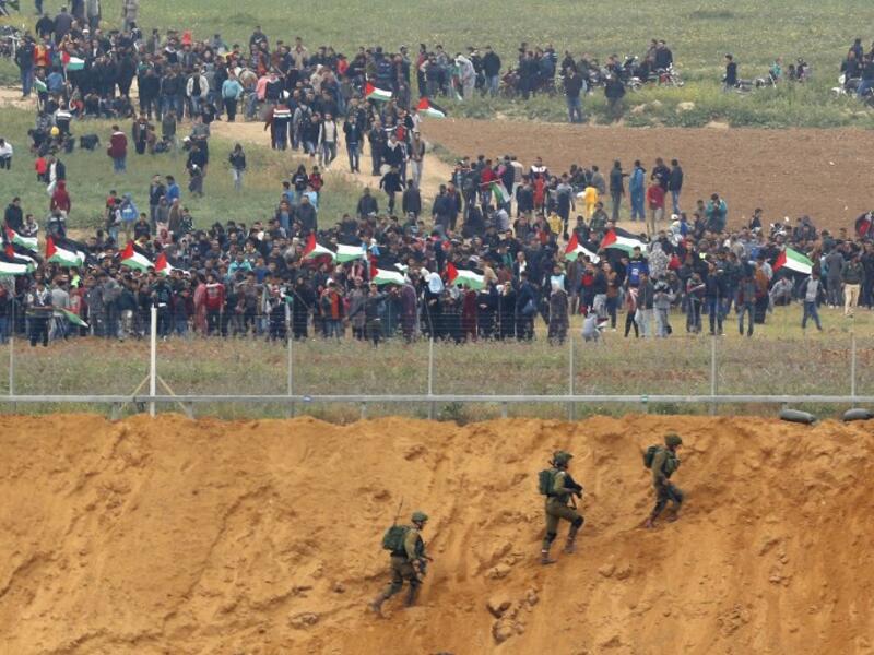 A picture taken on March 30, 2018 from the southern Israeli kibbutz of Nahal Oz across the border from the Gaza strip shows Palestinians participating in a tent city protest commemorating Land Day, with Israeli soldiers seen below in the foreground. 
(Jack GUEZ / AFP)
