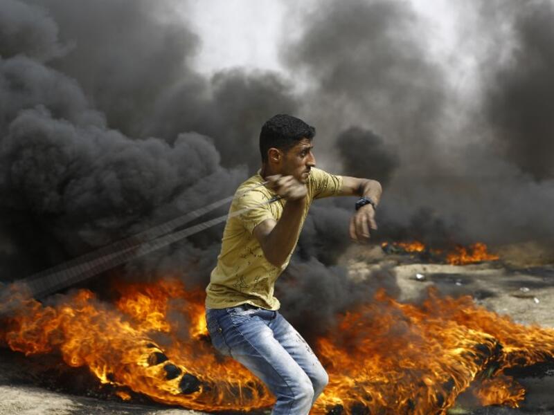 A Palestinian slings a shot by burning tires during clashes with Israeli forces across the border, following a demonstration calling for the right to return.
(MOHAMMED ABED / AFP)