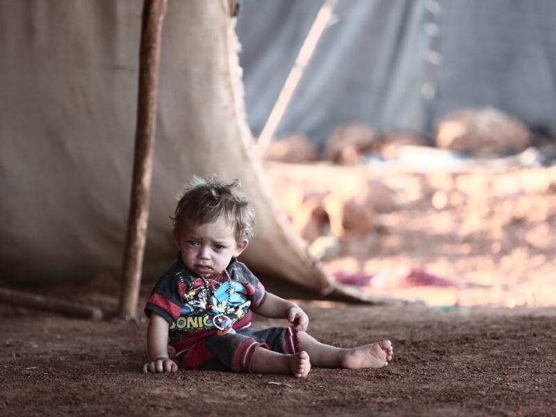 A child sits in front of a tent at a camp for the displaced from the rebel-held Syrian province of Idlib, at the village of al-Ghadfa, southeast of the province on September 2, 2018. (Nazeer AL-KHATIB / AFP)