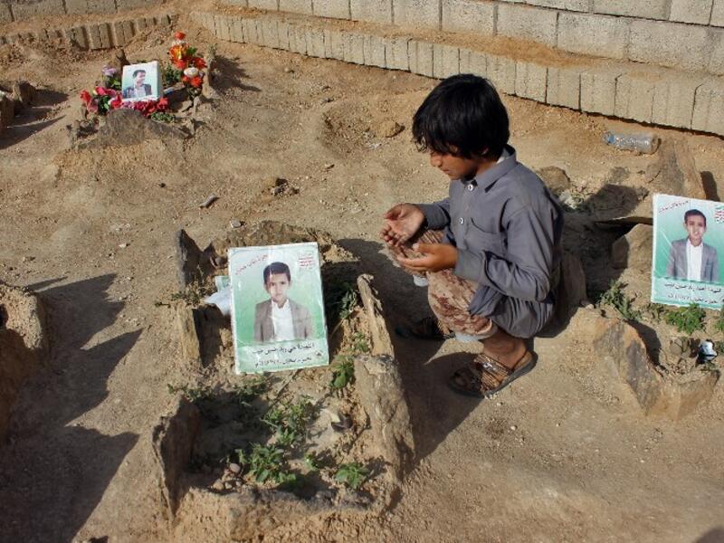 A Yemeni child recites a prayer by the graves of schoolboys who were killed while on a bus that was hit by a Saudi-led coalition air strike on the Dahyan market in August, at a cemetery in the Huthi rebels' stronghold province of Saada on September 4, 2018. 
STRINGER / AFP