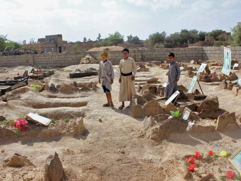 Yemeni children stand by the graves of schoolboys who were killed while on a bus that was hit by a Saudi-led coalition air strike on the Dahyan market in August, at a cemetery in the Huthi rebels' stronghold province of Saada on September 4, 2018. 
STRINGER / AFP