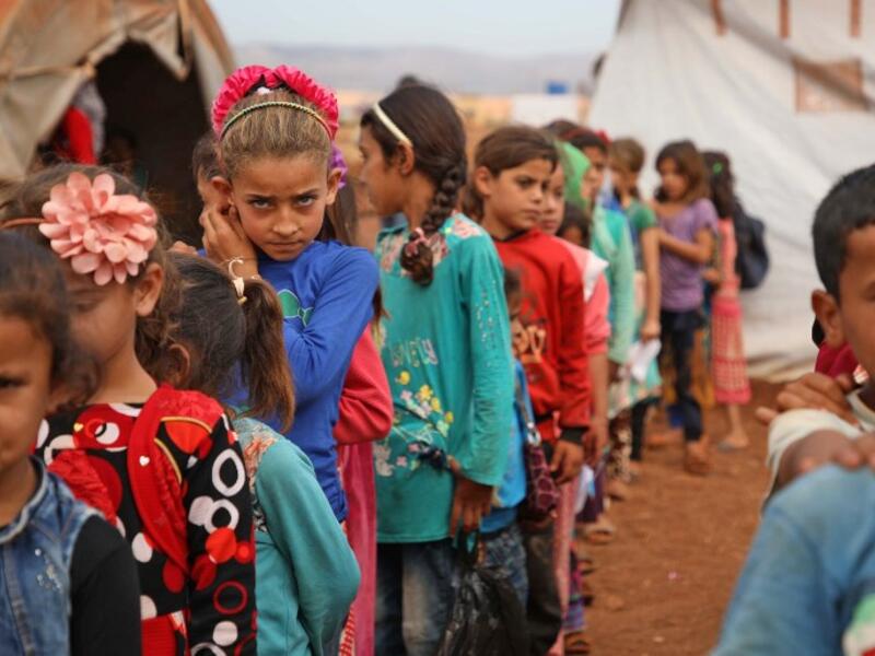 Syrian children who fled with their families from the northern countryside of Hama, line up in the yard of the makeshift school of "Zuhur al-Mustaqbal" (in Arabic "Flowers of the Future") in al-Jeneinah camp for displaced people in the village of Atme, in Syria's mostly rebel-held northern Idlib province, on October 1, 2018. Aaref WATAD / AFP