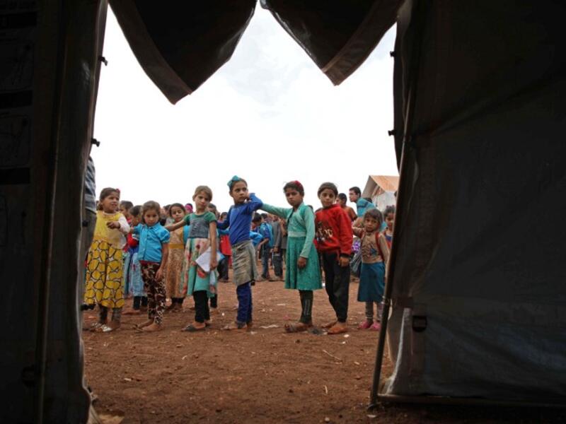 Syrian children who fled with their families from the northern countryside of Hama, line up in the yard of the makeshift school of "Zuhur al-Mustaqbal" (in Arabic "Flowers of the Future") in al-Jeneinah camp for displaced people in the village of Atme, in Syria's mostly rebel-held northern Idlib province, on October 1, 2018. Aaref WATAD / AFP