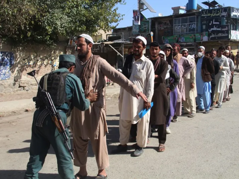 An Afghan policeman searches voters before casting their votes at a polling centre for the country's legislative election in Khost Province on October 20, 2018. 
FARID ZAHIR / AFP