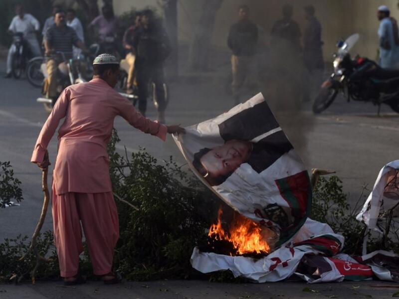 A supporter of Pakistan's religious hardline party Jamiat Ulema Islam (JUI) burns a poster of Pakistan's Prime Minister Imran Khan on a block street during a protest following the Supreme Court's decision to acquit Pakistani Christian woman Asia Bibi. (ASIF HASSAN / AFP)