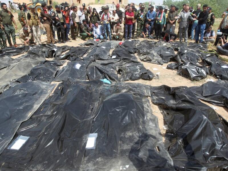 Iraqis mourn near body-bags containing the remains of people believed to have been slain by jihadists of the Islamic State (IS) group lying on the ground at the Speicher camp in the Iraqi city of Tikrit. (AHMAD AL-RUBAYE / AFP)