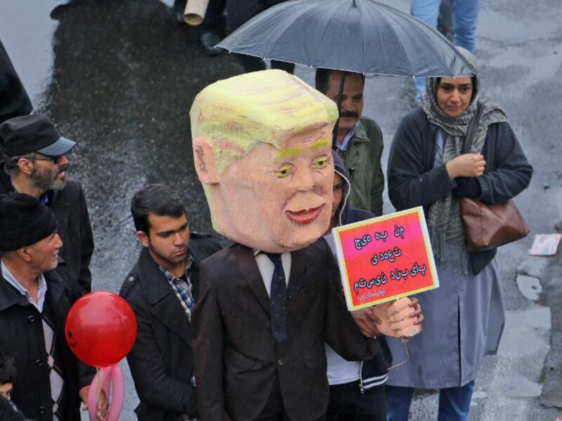 An Iranian man carries an effigy depicting US President Donald Trump carrying a sign reading in Persian "I am not bound by any commitment", during a ceremony celebrating the 40th anniversary of Islamic Revolution in the capital Tehran on February 11, 2019. 
ATTA KENARE / AFP