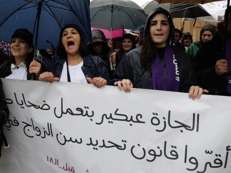 Lebanese demonstrators hold a banner as they participate in a march against marriage before the age of 18 in the capital Beirut on March 2, 2019. The banner in Arabic reads " Early marriage makes victims, change the law". 
ANWAR AMRO / AFP