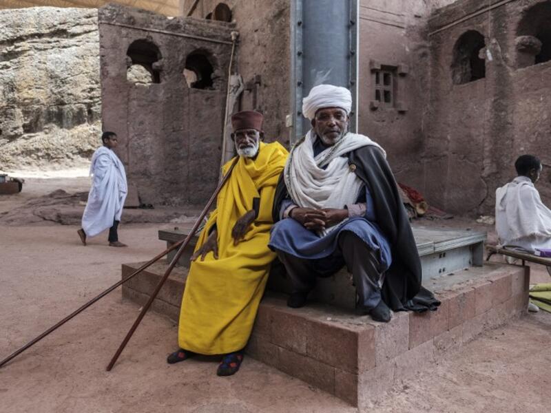 An Ethiopian Orthodox priest Mekonnen Fatne (R) poses near the church of Saint Mary which is covered by a shelter to protect its rock-hewn structure from erosion in Lalibela
EDUARDO SOTERAS / AFP