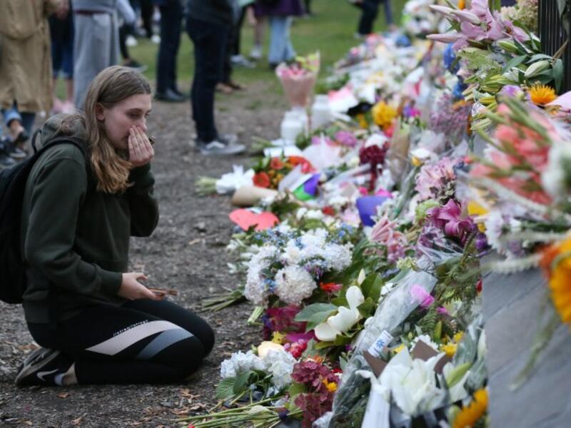 People pay their respects in front of floral tributes for victims of the March 15 mosque attacks, in Christchurch 
DAVID MOIR / AFP