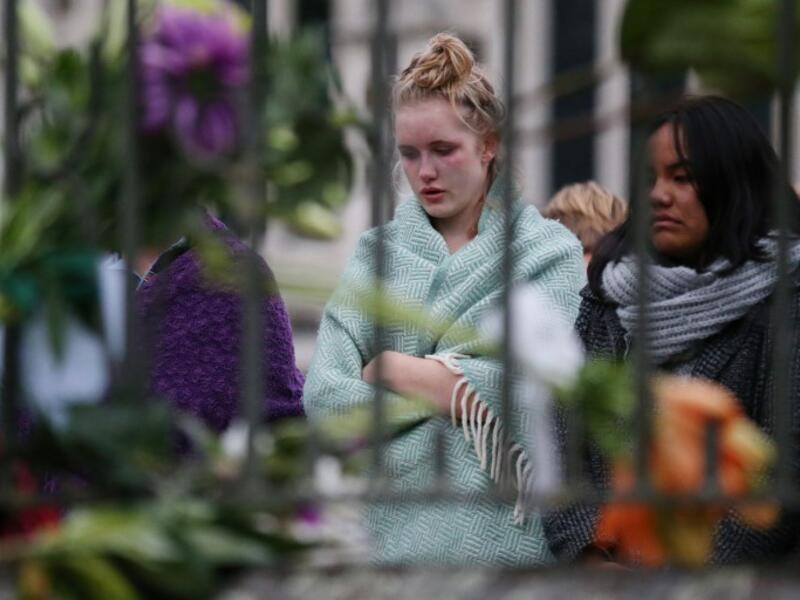 People pay their respects in front of floral tributes for victims of the March 15 mosque attacks, in Christchurch 
DAVID MOIR / AFP