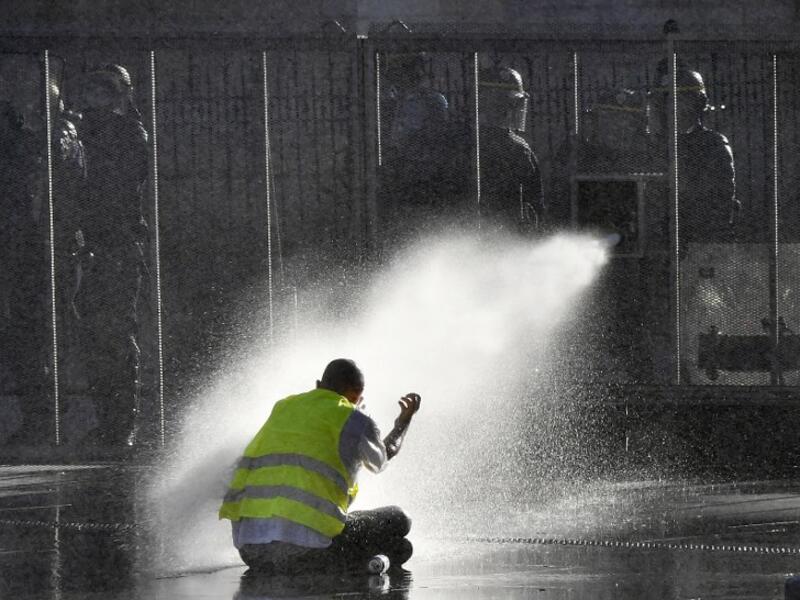 A protester sits on the ground while riot police uses a water cannon during an anti-government demonstration called by the 'Yellow Vest' movement, in Bordeaux, southwestern France, on March 23, 2019. (AFP/ File)