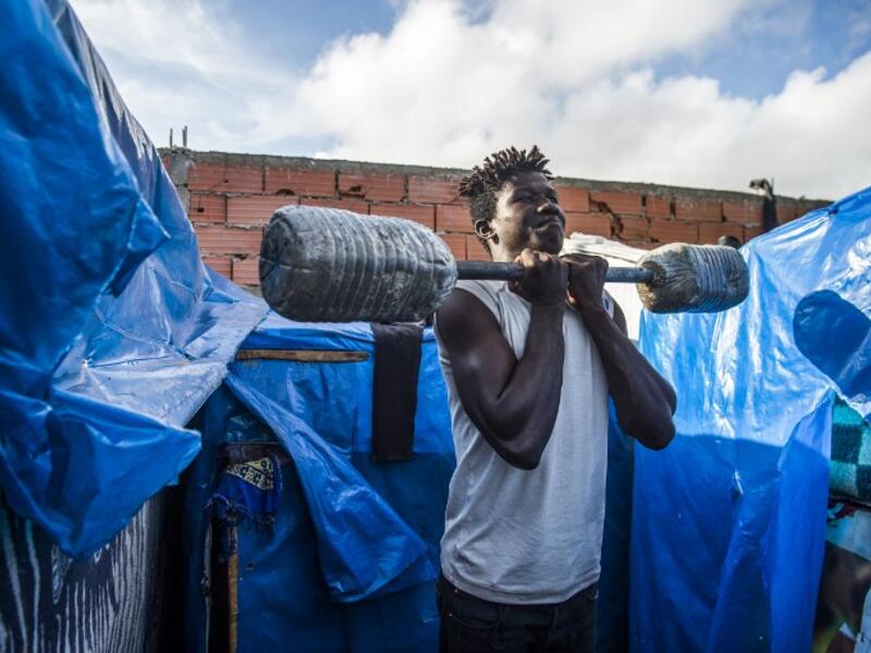 A sub-Saharan migrant lifts weights with a make-shift barbell between make-shift tents in the Oulad Ziane migrant camp in Casablanca on March 27, 2019. 
FADEL SENNA / AFP