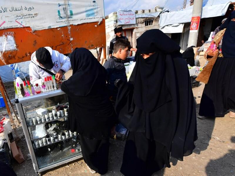 Women shop  from a stall in the souk or market of Al-Hol camp for displaced people in northeastern Syria
GIUSEPPE CACACE / AFP