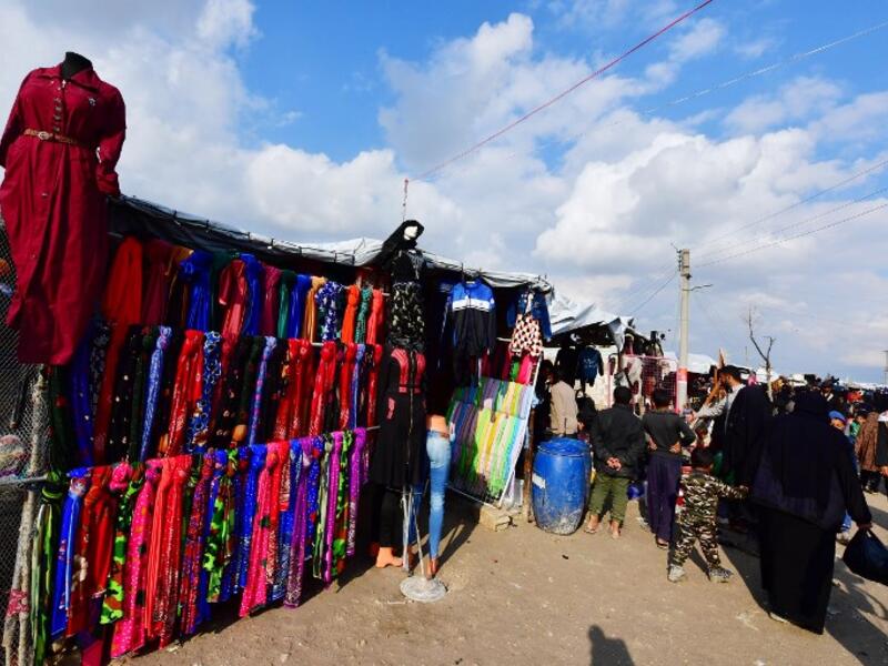 People walk past clothing stalls in the souk or market of Al-Hol camp for displaced people in northeastern Syria
GIUSEPPE CACACE / AFP