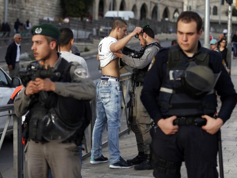 Israeli security forces body-check a Palestinian young man at the entrance of Damascus Gate, outside Jerusalem's Old City, on March 9, 2016. (AFP/Ahmad Gharabli)