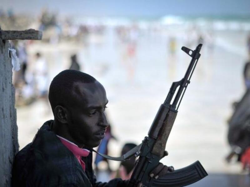 An armed guard stands watch as people celebrate Eid al-Fitr on Lido beach in Mogadishu. (AFP/AU/UN)
