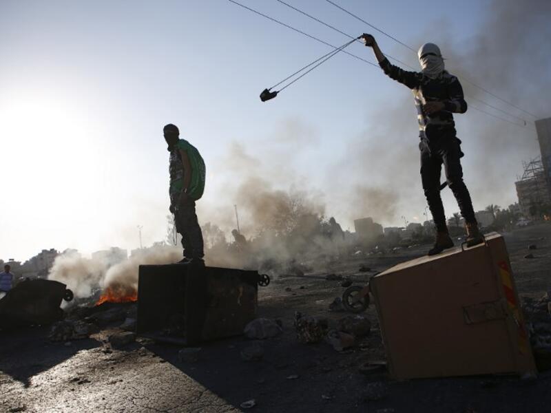 A Palestinian protestor uses a slingshot during clashes with Israeli forces near an Israeli checkpoint in the West Bank city of Ramallah. (ABBAS MOMANI / AFP)