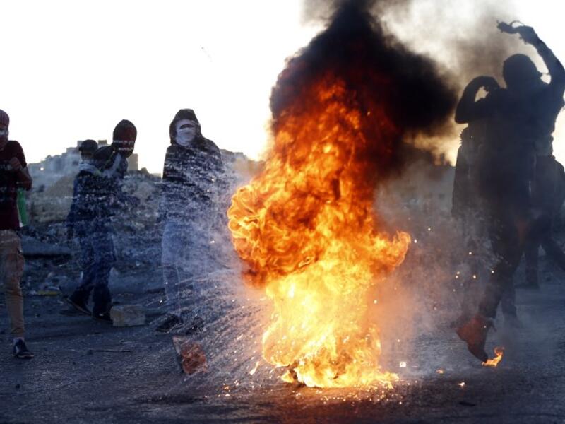 A Palestinian demonstrator kicks a burning tire during clashes with Israeli forces near an Israeli checkpoint in the West Bank city of Ramallah following the U.S. president's controversial recognition of Jerusalem as Israel's capital. 
(ABBAS MOMANI / AFP)