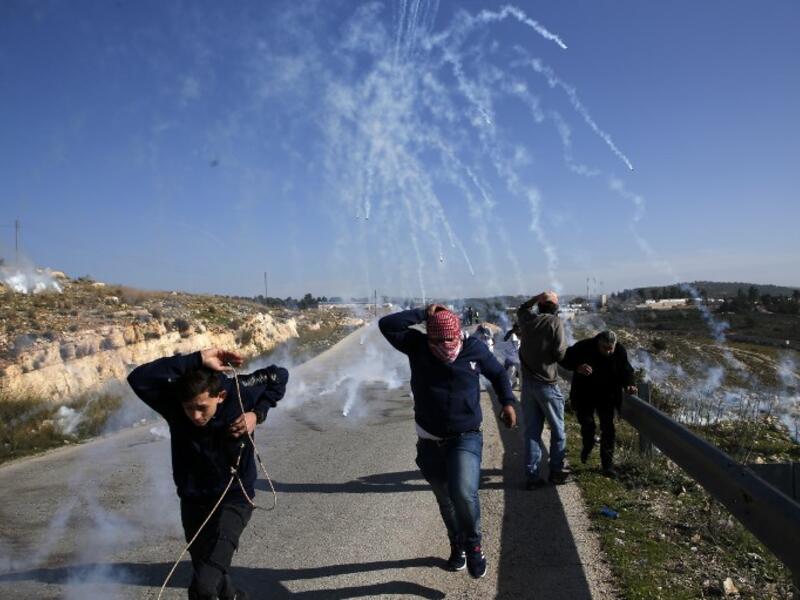 Palestinians run for covers from smoke-grenades during clashes with Israeli security forces following a demonstration in support of Palestinian prisoners on Jan. 13, 2018 (ABBAS MOMANI / AFP)