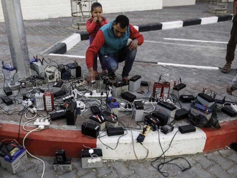 Palestinian charge their mobile phones from batteries, a free service offered in a neighborhood suffering from power cuts, in Gaza City on Feb. 1, 2018 (MOHAMMED ABED / AFP)