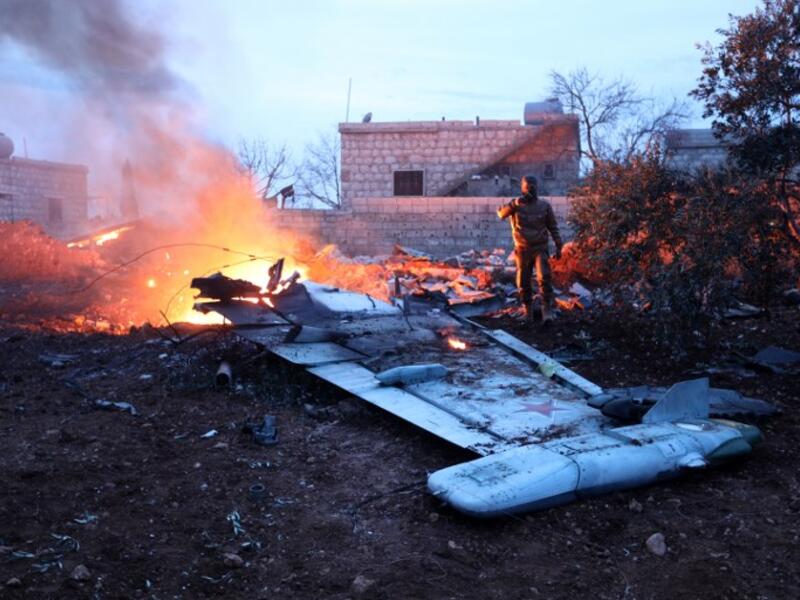 A picture taken on February 3, 2018, shows a Rebel fighter taking a picture of a downed Sukhoi-25 fighter jet in Syria's northwest province of Idlib. Rebel fighters shot down a Russian plane over Syria's northwest Idlib province and captured its pilot, the Syrian Observatory for Human Rights said. (OMAR HAJ KADOUR / AFP)