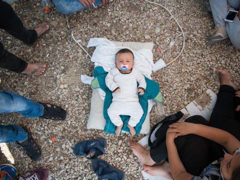 A Syrian baby lies in gravel at Kara Tepe camp, where its parents are unable to feed it. (Facebook)