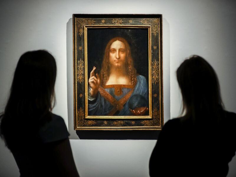 Christie's employees pose in front of a painting entitled Salvator Mundi by Italian polymath Leonardo da Vinci at a photocall at Christie's auction house in central London on October 22, 2017 ahead of its sale at Christie's New York on November 15, 2017. (AFP/Tolga Akmen)