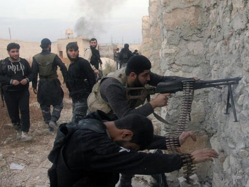 Syrian rebel fighters shoot through a hole in a wall towards forces loyal to the regime in Aleppo.(AFP / File)

