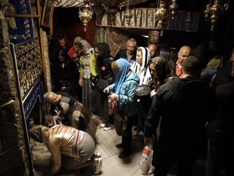 A group of tourists and pilgrims visit the Grotto, believed to be the exact spot where Jesus Christ was born, as others pray at the Church of the Nativity in the West Bank city of Bethlehem. Thomas Coex/AFP
