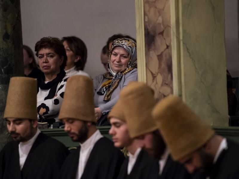 People look at whirling dervishes performing during a ceremony marking the anniversary of the death of Jelaleddin Mevlana Rumi, Sufi mystic, poet and founder of the sufism on December 16, 2018 at Galata Mevlihanesi in Istanbul. 
Yasin AKGUL / AFP