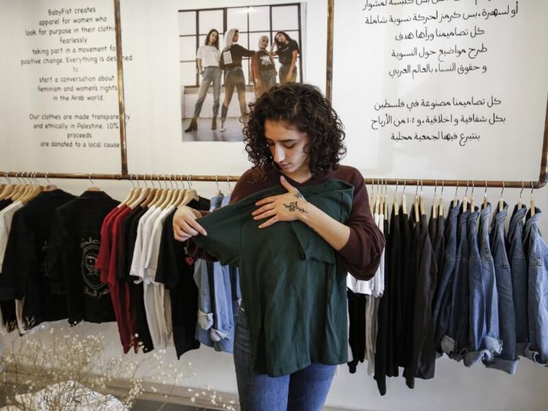 Palestinian fashion designer Yasmeen Mjalli speaks while standing in her clothing shop where her label collection "BabyFist" carrying anti-sexual harassment slogans is showcased, in Ramallah 
ABBAS MOMANI / AFP