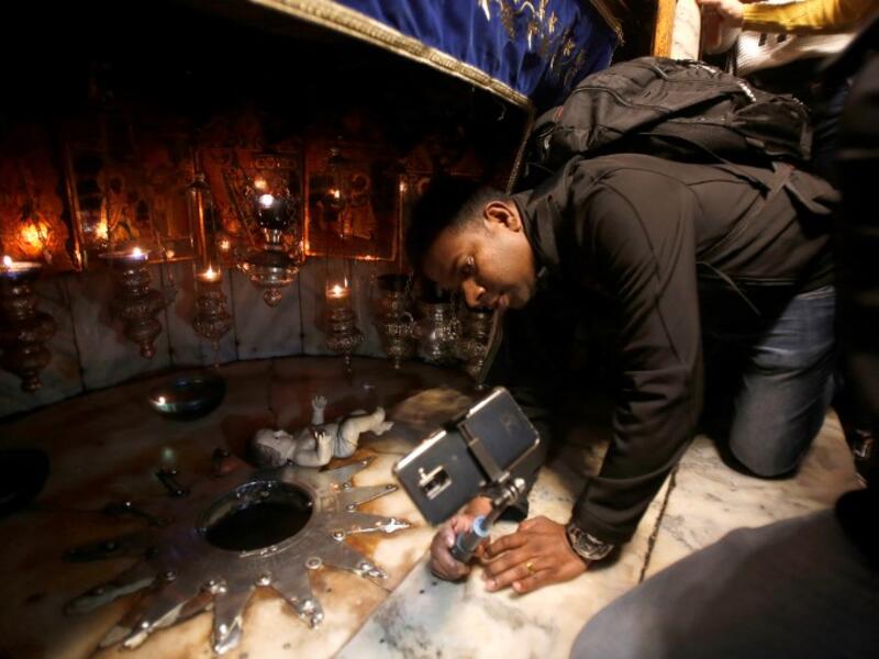 A man takes a selfie picture as tourists and pilgrims visit the Grotto on December 22, 2018, three days ahead of the Christmas celebration. Musa Al Shaer/AFP 