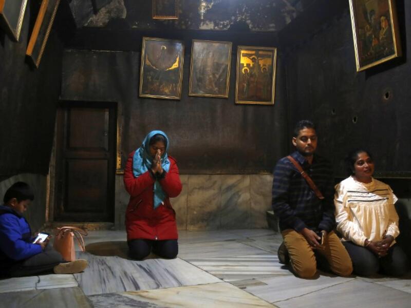 Christian worshipers pray inside the Grotto, believed to be the exact spot where Jesus Christ was born, at the Church of the Nativity in the biblical West Bank city of Bethlehem, on December 22, 2018, three days ahead of the Christmas celebration.  Musa Al Shaer/AFP
