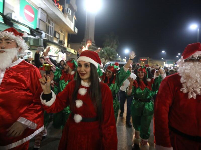 Syrian people dressed as Santa Claus walk in the capital Damascus' central neighbourhood of Qassaa to celebrate Christmas early on December 22, 2018. 
LOUAI BESHARA / AFP