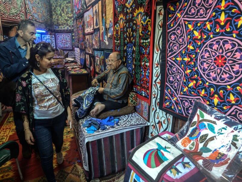 Customers walk in the shop of an Egyptian craftsman as he weaves a tapestry in his shop in Khayamiya Street, or the Street of Tent-makers, in the old city of the Egyptian capital Cairo on December 18, 2018. 
Mohamed el-Shahed / AFP